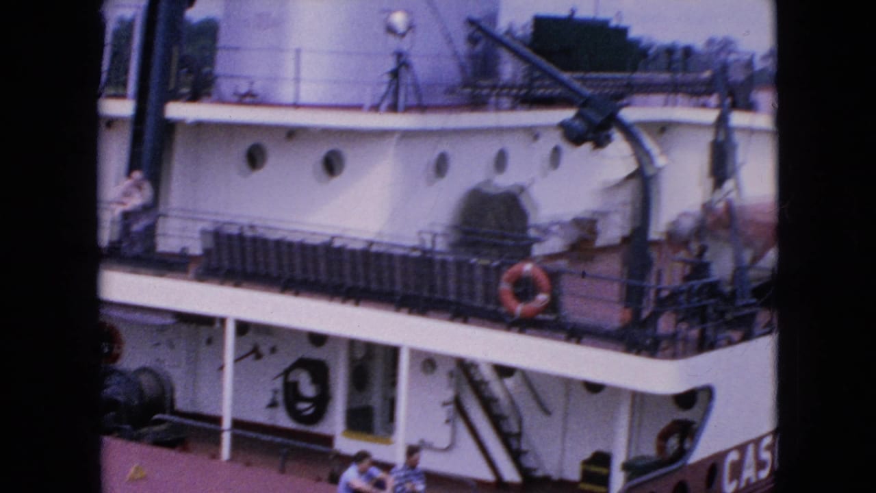 1964 8mm frame showing the upper deck of the Cason J. Callaway vessel at or near a dock or lock in Niagara Falls, New York, with deck equipment and partial name lettering visible.