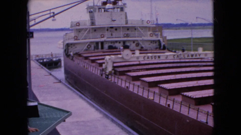 The final 1964 frame holds on the Cason J. Callaway at the dock, showing the freighter's name, brown cargo covers, white superstructure, pier surface, and muted waterfront background.
