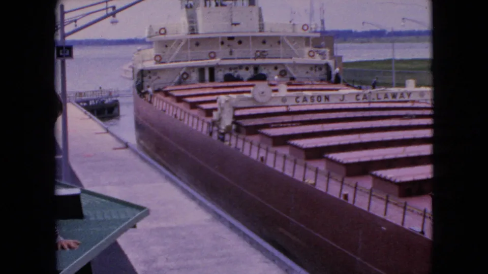 Final frame of the 1964 dockside shot shows the Cason J. Callaway at rest beside the pier, with empty holds, white superstructure, water, and shoreline in view.