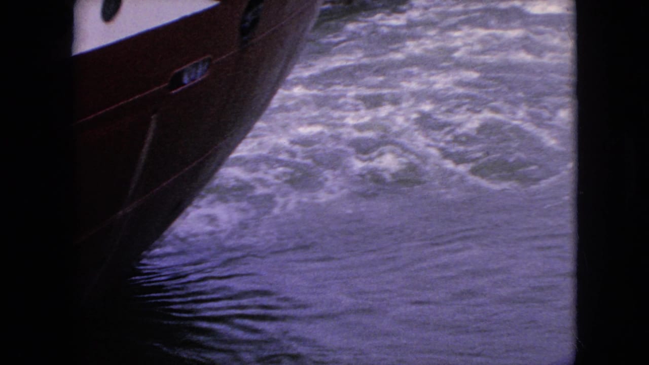 1964 8mm travel footage near Niagara Falls, New York, showing the red hull of a boat passing close to churning water.