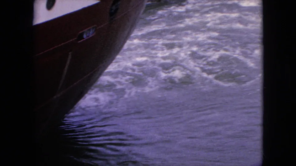 1964 8mm travel footage near Niagara Falls, New York, showing the red hull of a boat passing close to churning water.