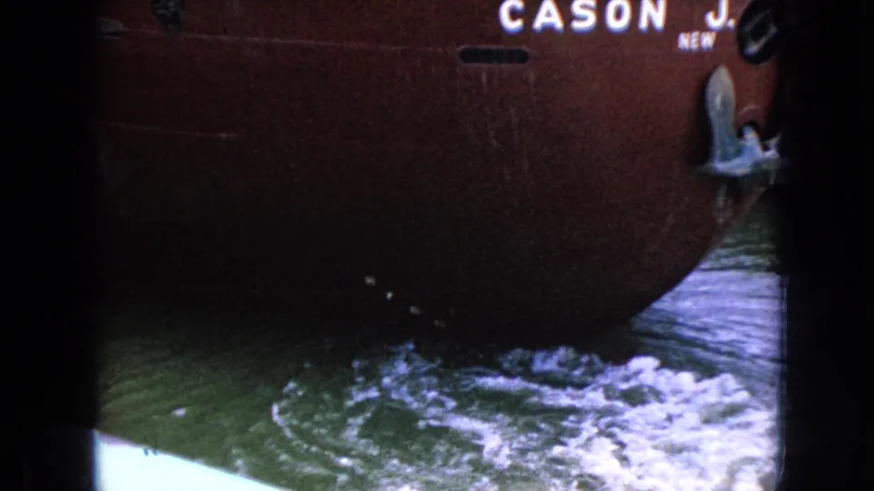 A close, partly vignetted 8mm view shows the red hull and bow section of the CASON J. CALLAWAY above disturbed green water and white wake.