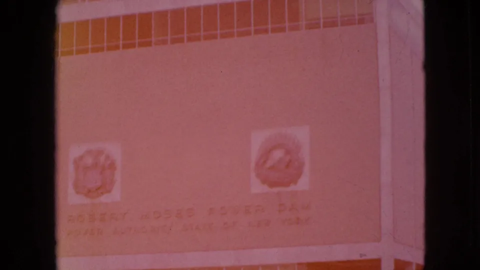 Orange-tinted 8mm frame showing a building or wall sign that appears to read Robert Moses Power Dam, supporting the Niagara Falls-area setting.