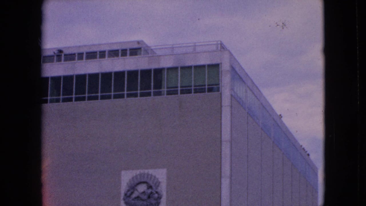 Modernist building with circular wall emblem above concrete waterworks structure.