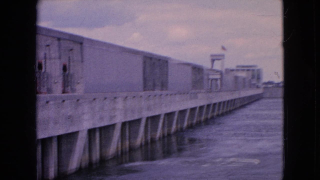 Concrete structure receding along the water with distant platform elements.