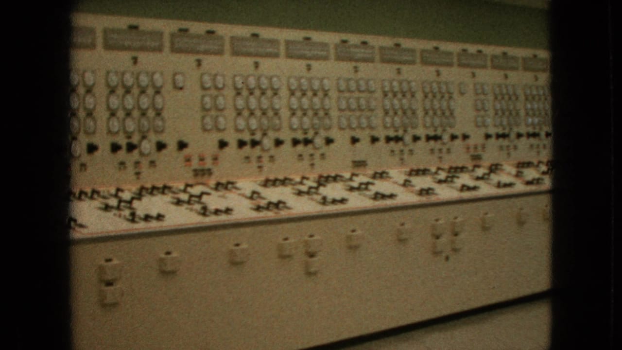 Wall-length control console seen through dark film-frame edges.