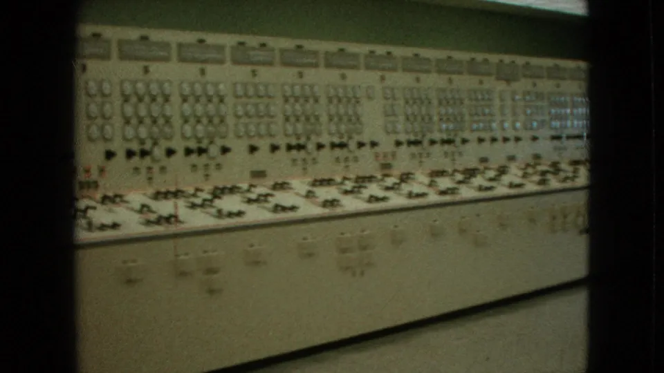Closer 1964 8mm view of the Niagara Falls control-room console, emphasizing analog dials, switch rows, indicator lamps, and beige equipment panels.