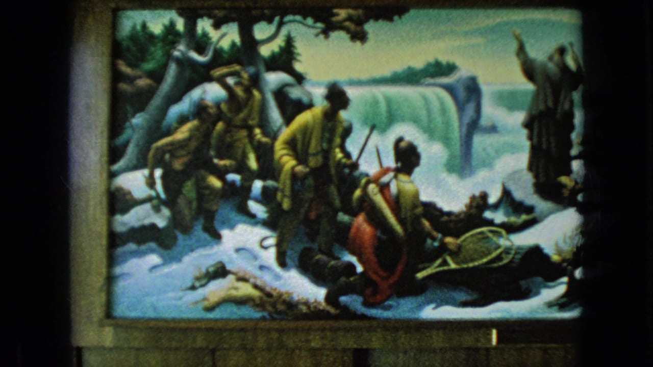 1964 Niagara Falls, New York 8mm frame showing a painted or staged snowy explorer tableau with costumed figures near a waterfall backdrop and dark projection borders.