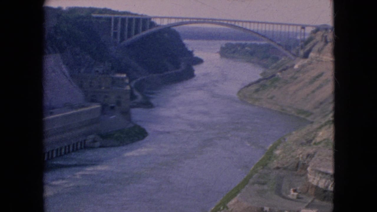 River flowing through a rocky gorge beneath a high arched bridge.