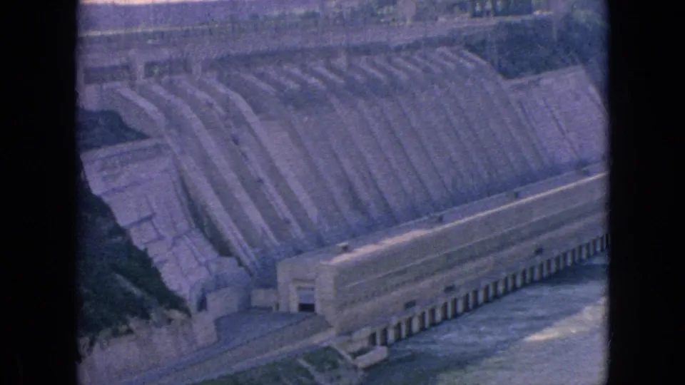 1964 Niagara Falls, New York footage frame with the concrete dam, stepped spillway, lower water channel, and dark vertical film border visible.