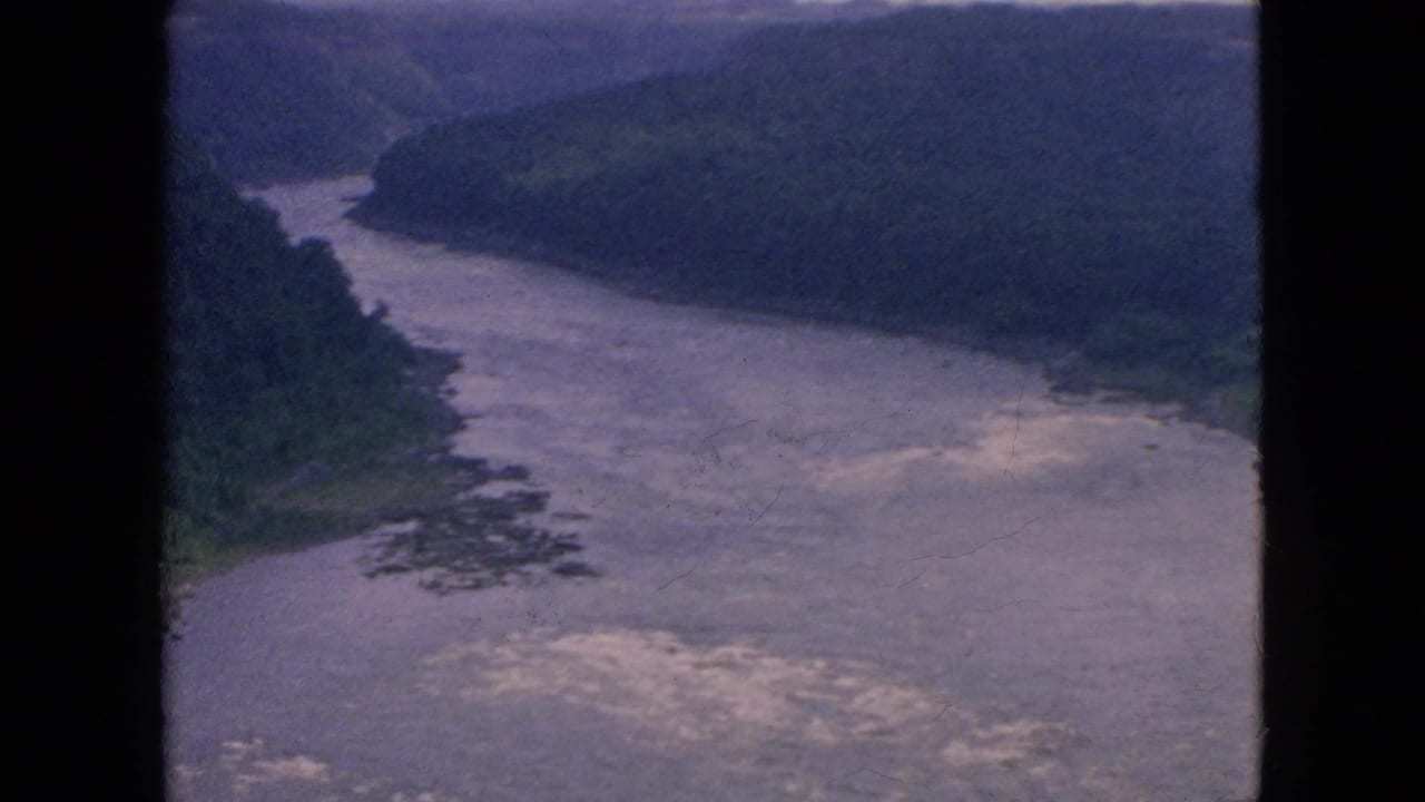 Wide river bend with pale whitewater and wooded hills on both sides.
