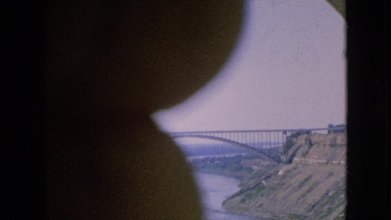 Steel bridge and river gorge seen behind a large dark foreground obstruction.