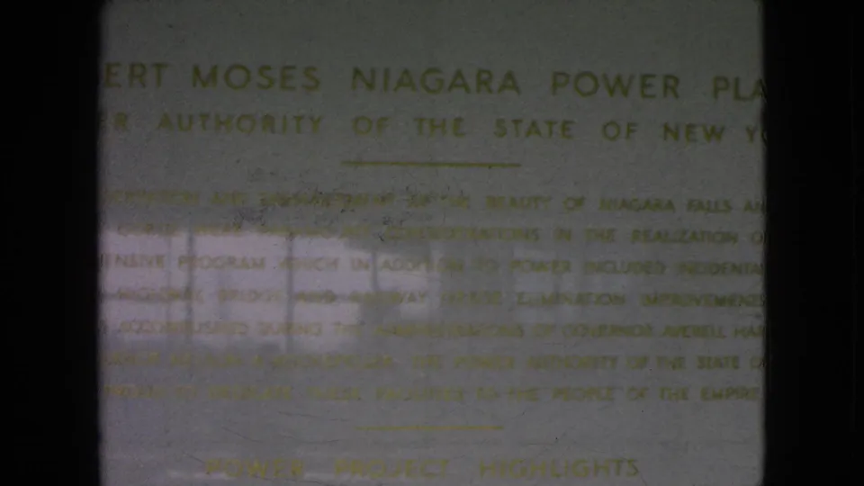 Final 8mm frame showing the Robert Moses Niagara Power Plant heading and inscription text on a pale wall, with dark film borders and uneven reflected light visible in the scan.