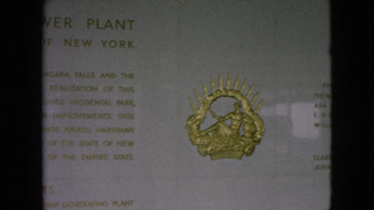 1964 8mm frame of the Moses Niagara Power Plant plaque, with the gold emblem more clearly visible below the printed text.
