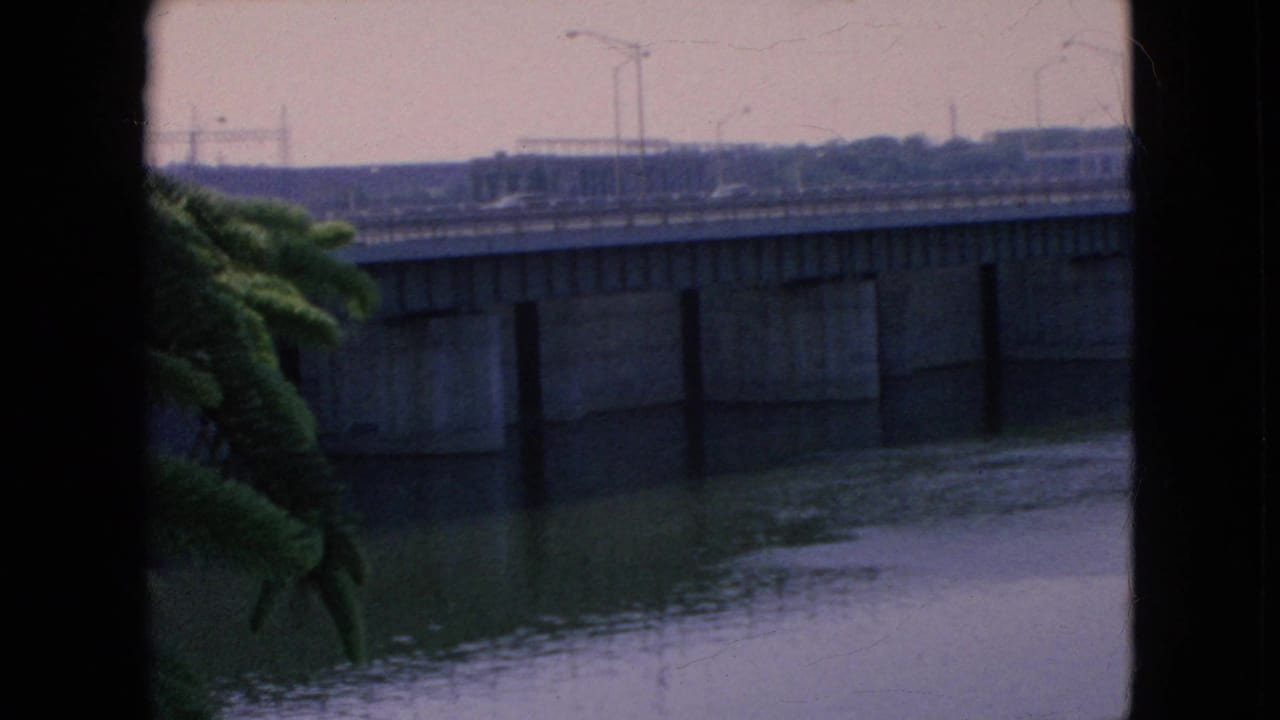 Concrete bridge over water with autos and lamp posts visible above the span.