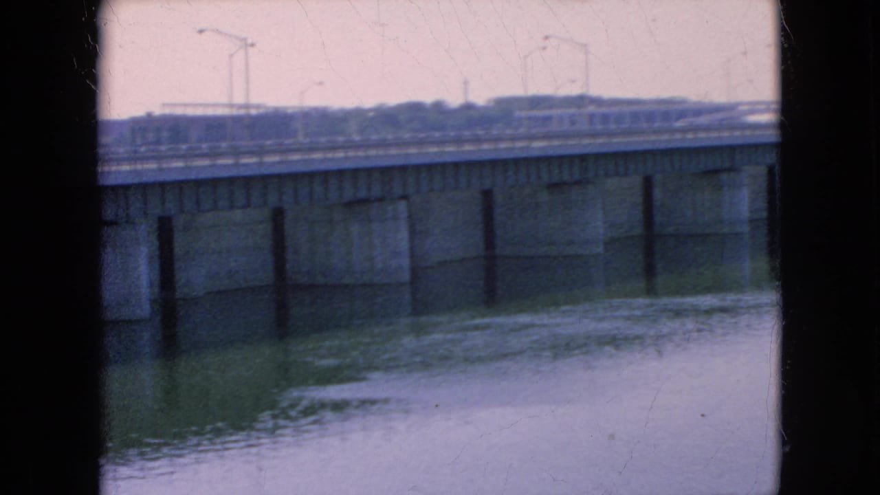 A final 1964 Niagara Falls, New York frame shows the bridge and river from a similar angle, with roadway lights, distant structures, and muted 8mm color.