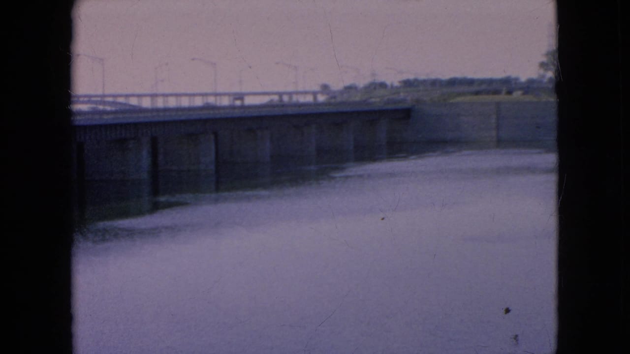 Final frame of the 1964 Niagara Falls area home movie, with the bridge extending across calm river water and dark 8mm gate edges visible.