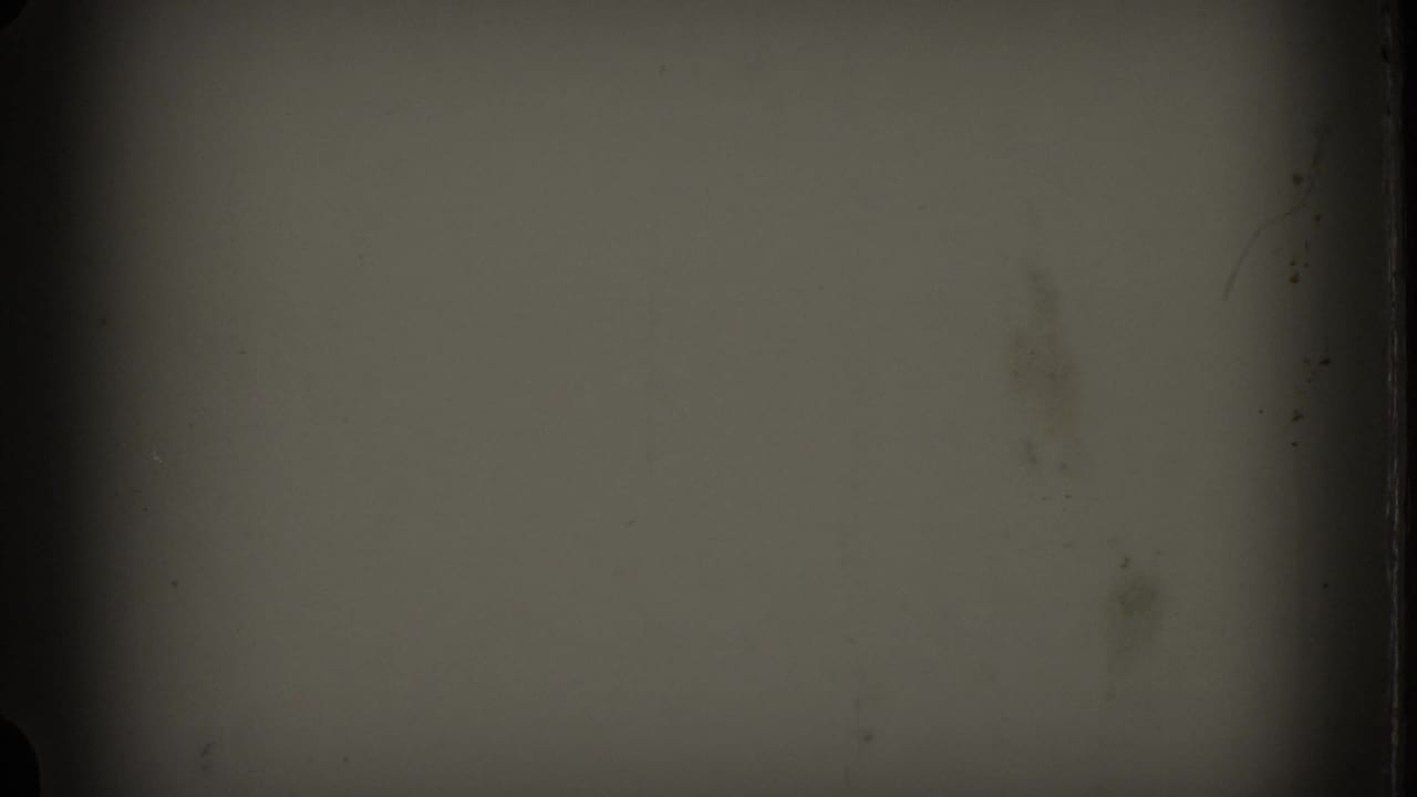 End frame from the 8mm clip showing a largely obscured, darkened film area with soft green-gray exposure and visible frame-edge wear.