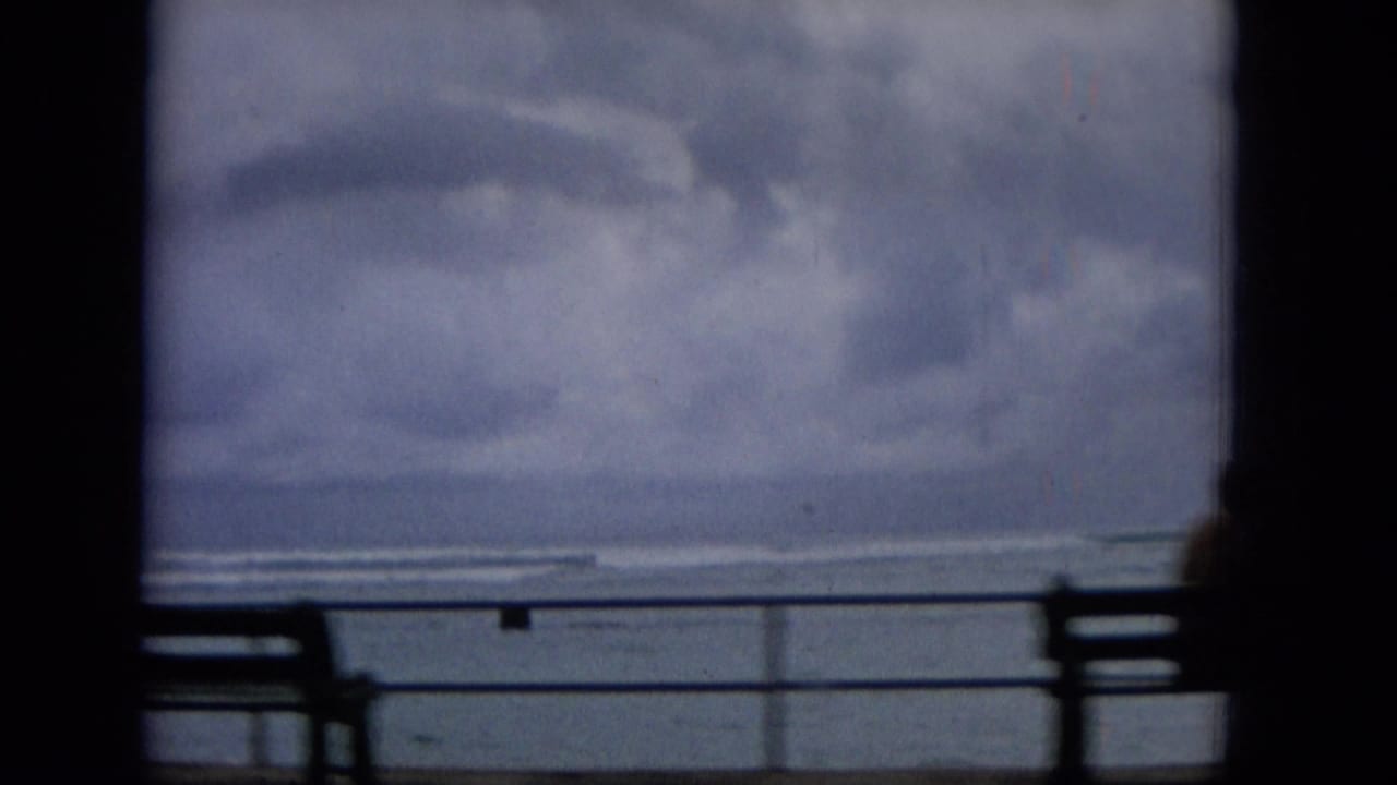 Seaside railing and bench silhouettes against a cloudy ocean horizon.
