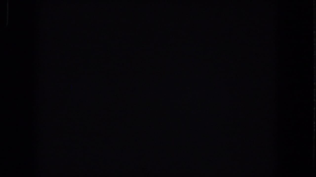 Mostly dark frame with faint vertical film or exposure marks.