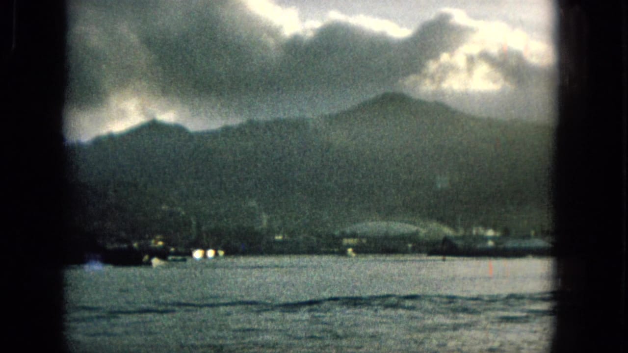Distant mountains and shoreline lights across water beneath a cloudy sky.