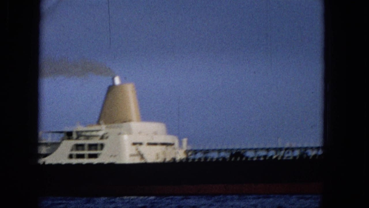 1965 Hawaii 8mm frame with the tanker cropped closer, emphasizing the white superstructure, dark hull, railings, and smoke drifting from the funnel.