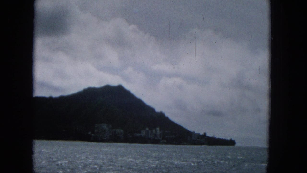 Dark hillside above choppy ocean under heavy clouds.