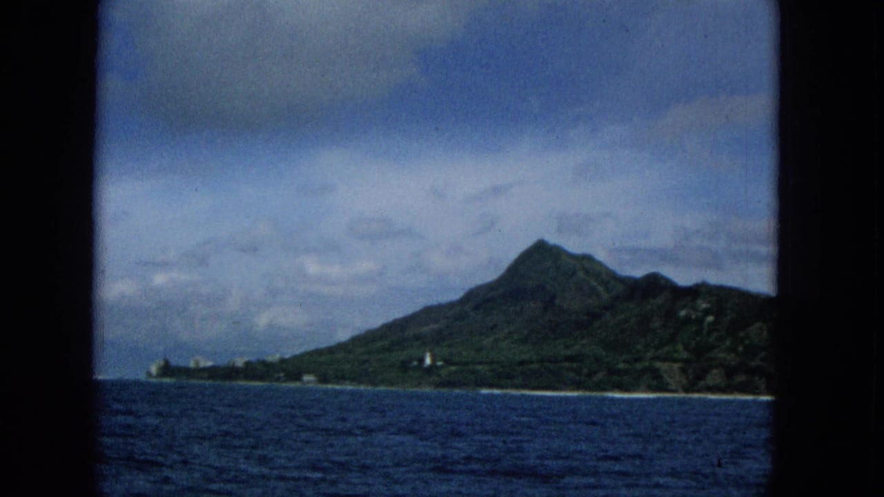 Mountainous island shoreline seen across open water with a dark vertical frame edge.