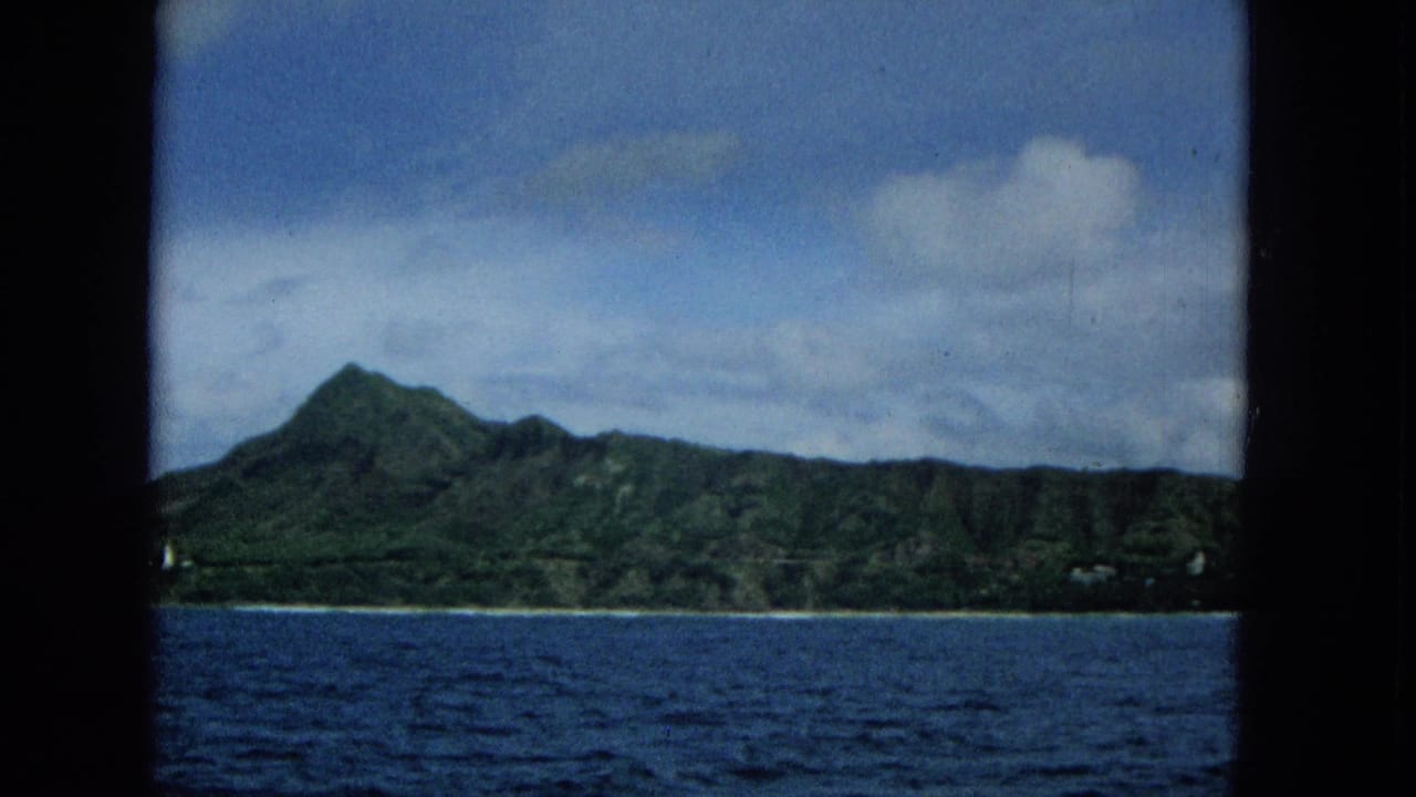 1965 Hawaii travel footage shows a prominent green peak and ridgeline on Molokai, filmed from a moving boat across the ocean.
