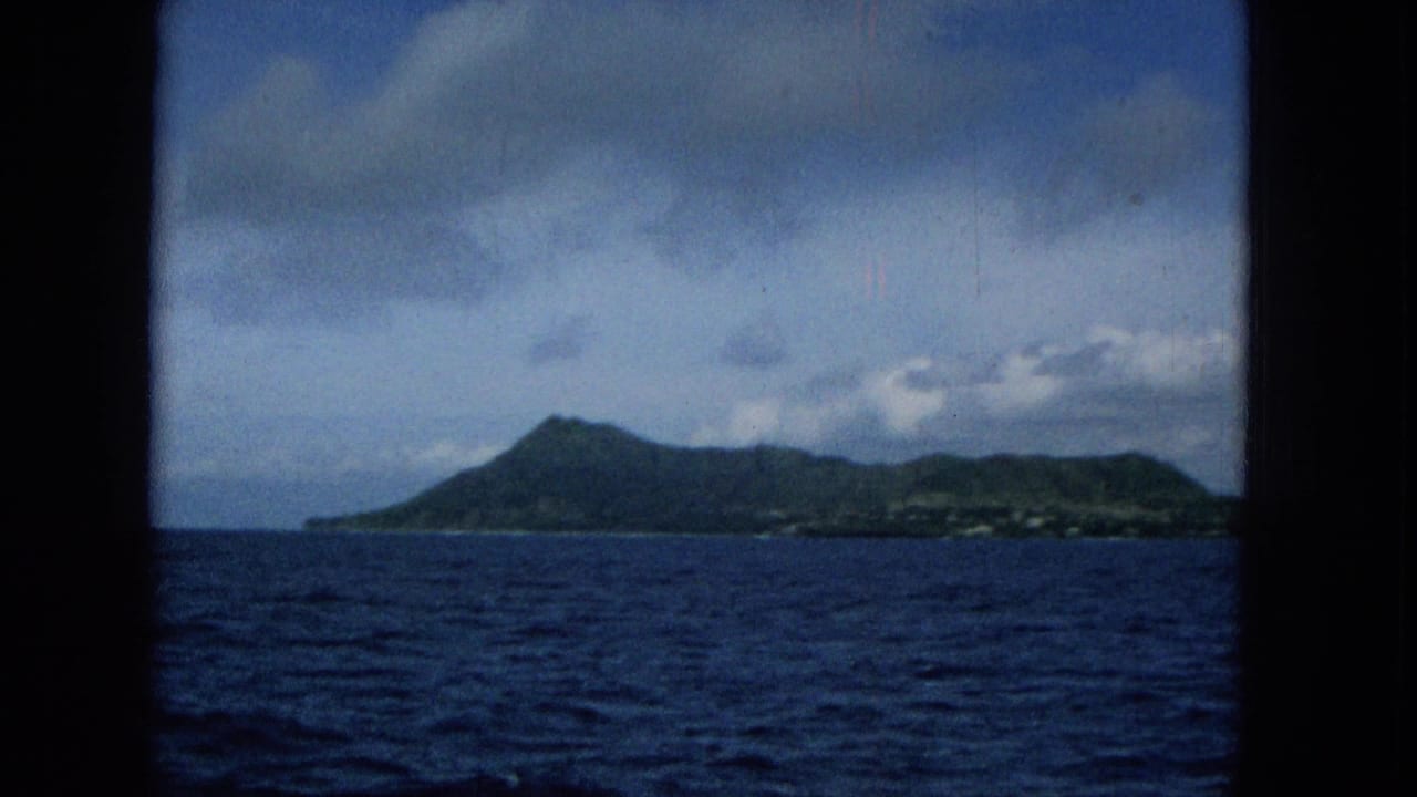 1965 Super 8 view toward Molokai from a boat, with blue ocean in the foreground, green slopes on the horizon, and dark window framing at the sides.