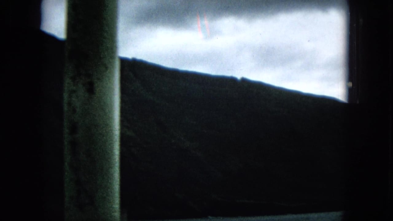 Shadowed hillside and cloudy sky divided by a vertical window post.