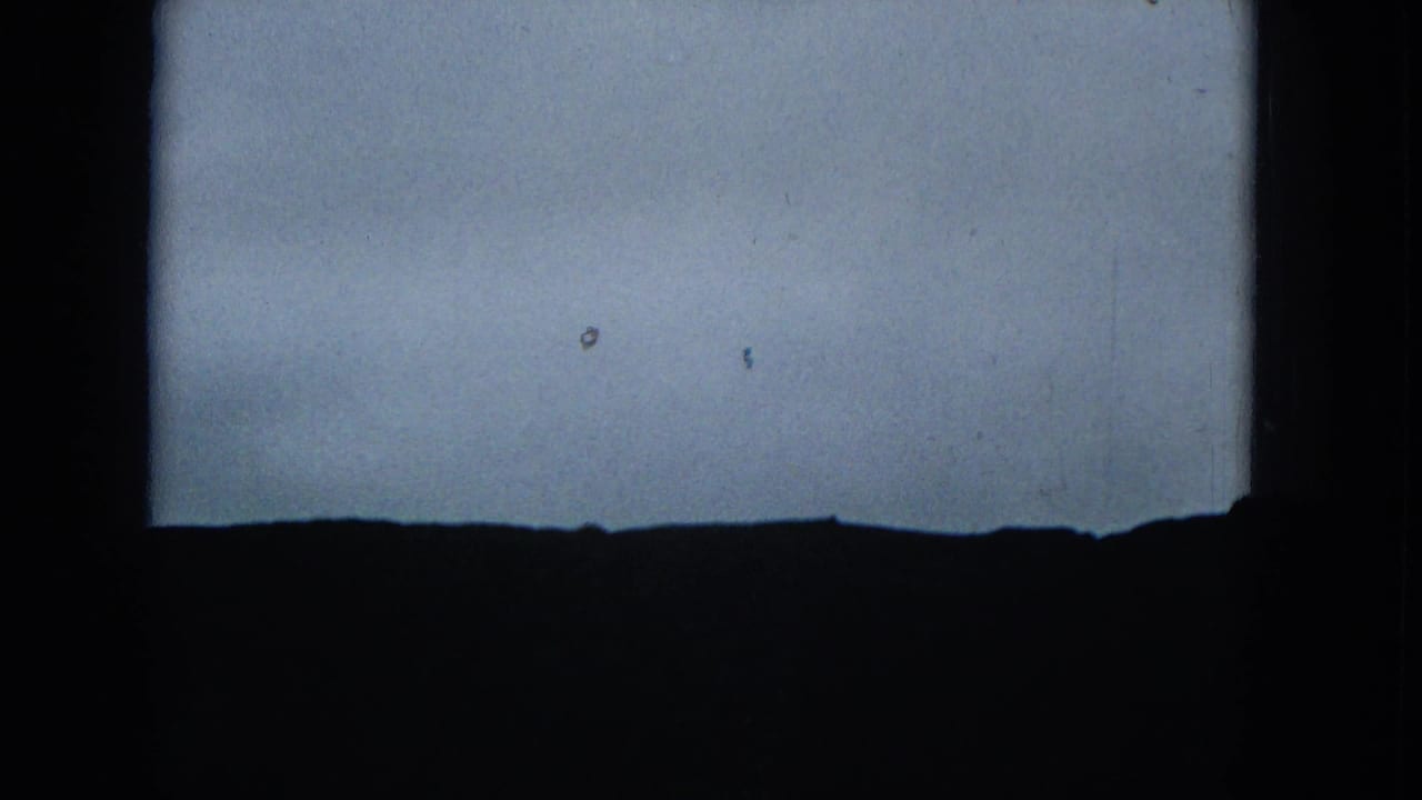 Low dark ridgeline against a pale sky with heavy shadowed borders.