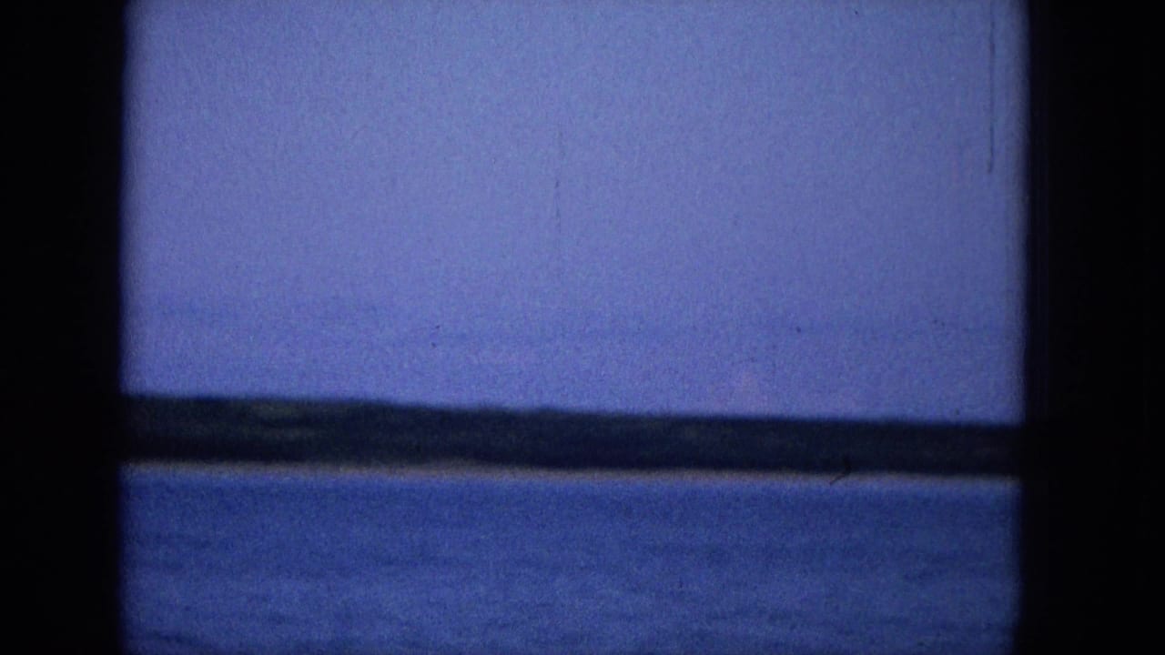 Calm blue water and a distant dark horizon divided by a central dark vertical bar.