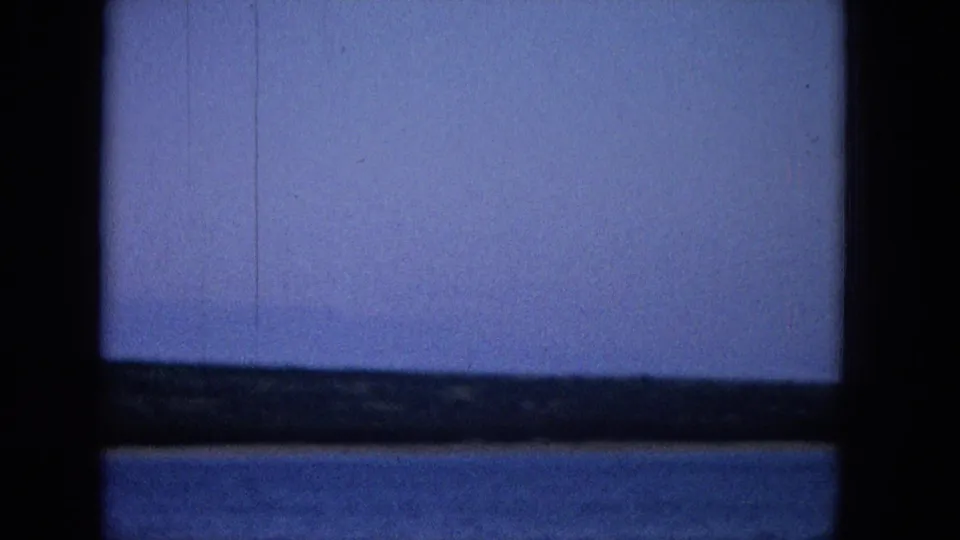 A soft Super 8 view shows a low shoreline across blue water, enclosed by dark vertical and horizontal boat or window framing.