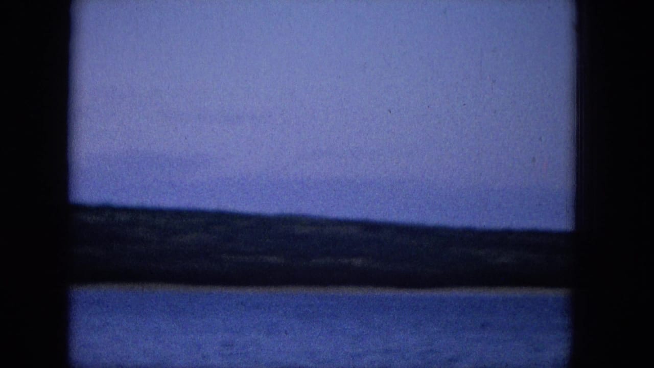 Blue water and low dark shoreline framed by vertical and horizontal window bars.