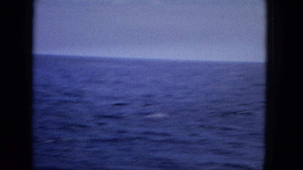 Open ocean and horizon framed by dark film borders.