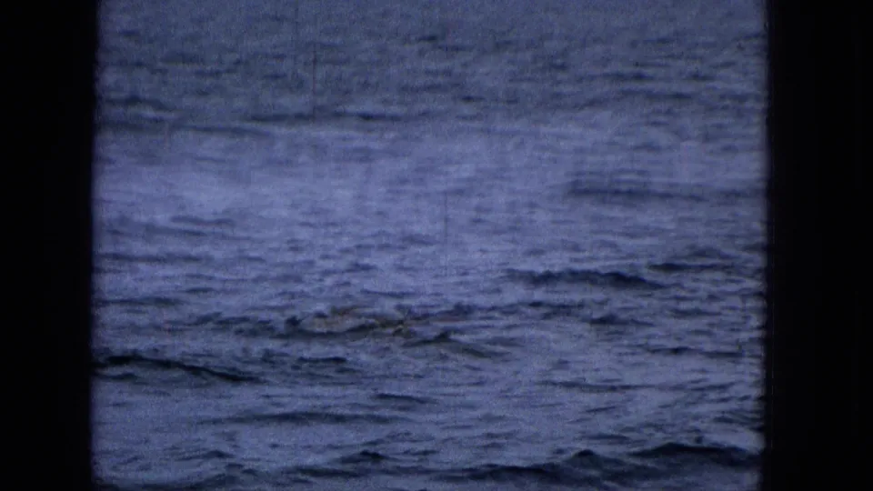Choppy blue ocean is seen through dark vertical framing, with no identifiable vessel name, landmark, or person visible in this sampled frame.