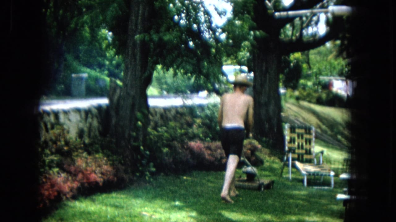 In a 1965 United States backyard scene, a shirtless man in dark shorts and straw hat walks toward a manual mower near a woven lawn chair under shade trees.