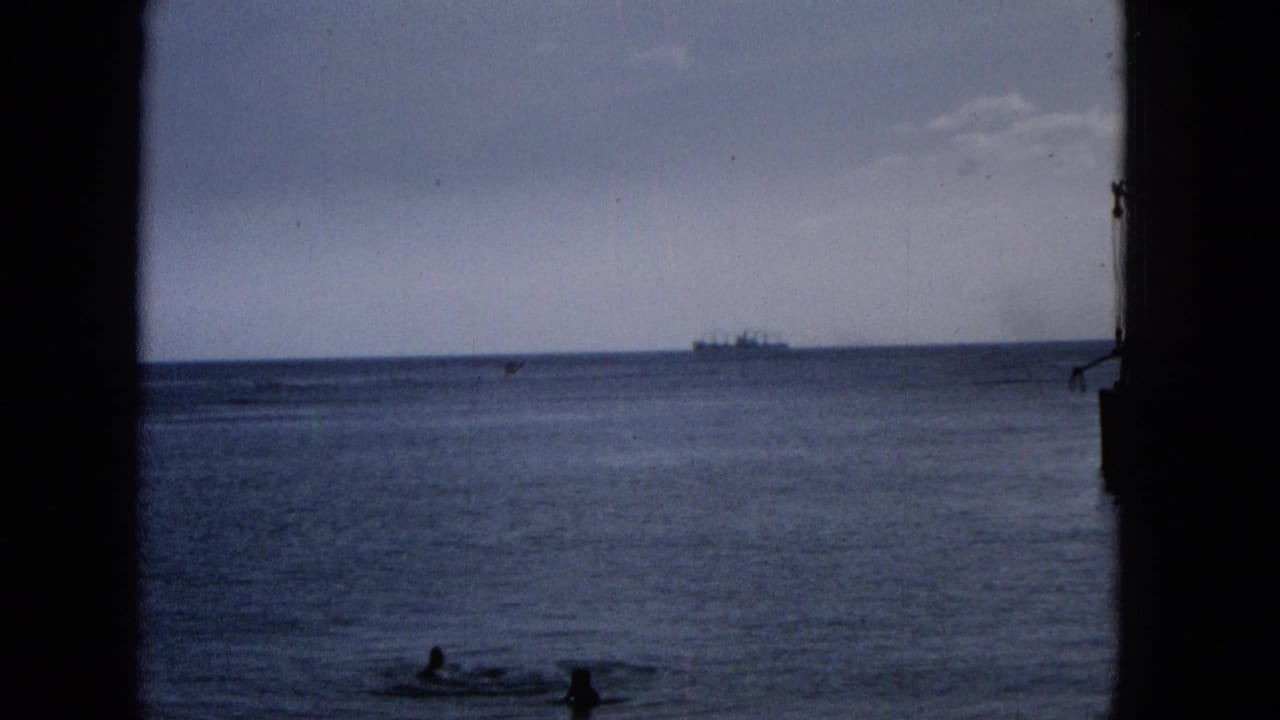Distant ship on the horizon with swimmers low in frame, seen through a dark vertical opening.