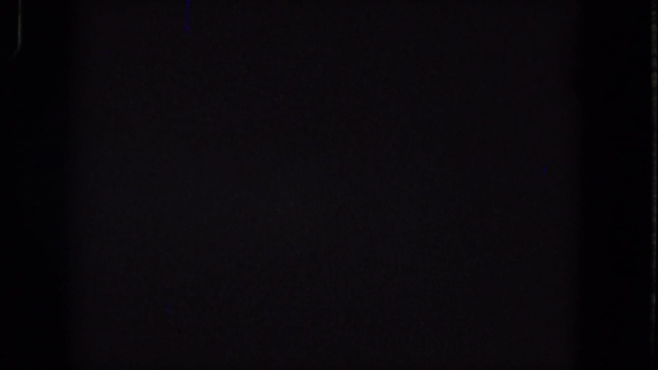 Dark 1965 Super 8 source frame showing near-black exposure, subtle grain, and faint vertical edge marks without identifiable people or place details.