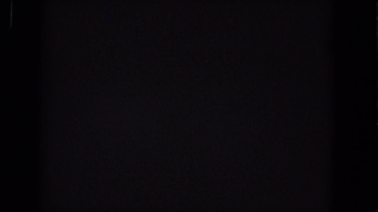 Dark frame with faint vertical blue artifact and minimal visible detail.