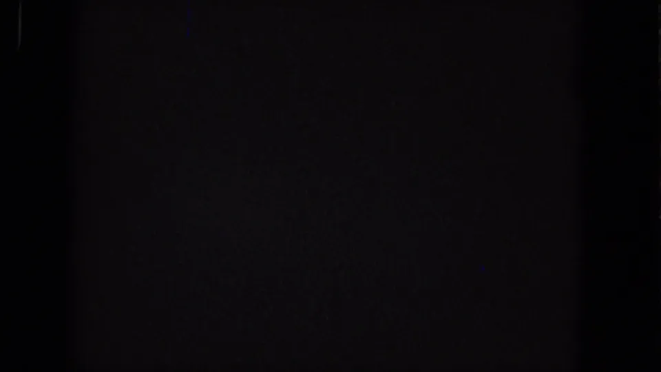 Near-black Super 8 frame from the 1965 source with faint blue vertical artifacting, grain, and no identifiable subject matter.