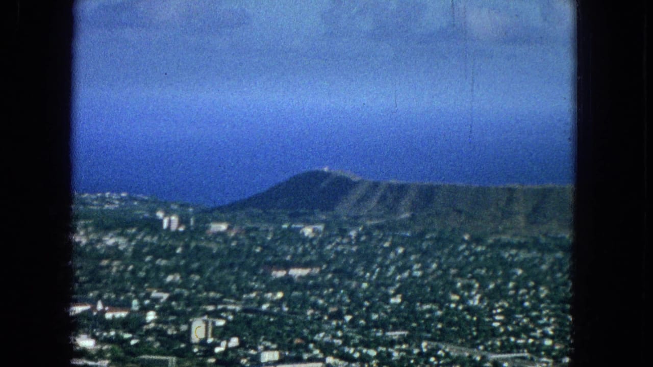 Elevated city view toward Diamond Head crater under blue sky.