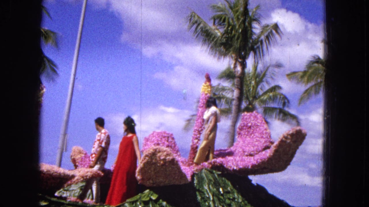 Floral parade float with several participants passing palm trees.