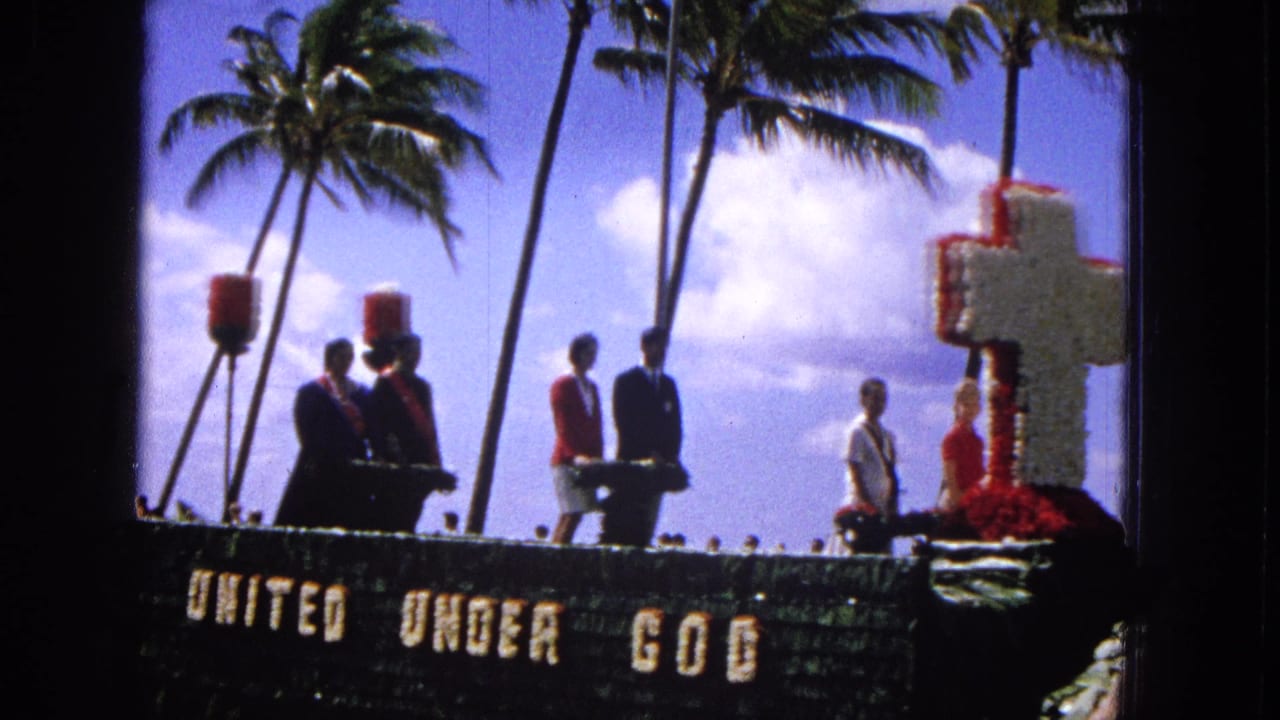 1965 Molokai Easter parade view showing people standing on a decorated float with a floral cross and "UNITED UNDER GOD" text against palm trees.