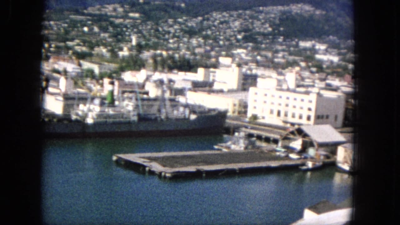 Harbor pier and docked cargo ship beside waterfront buildings.