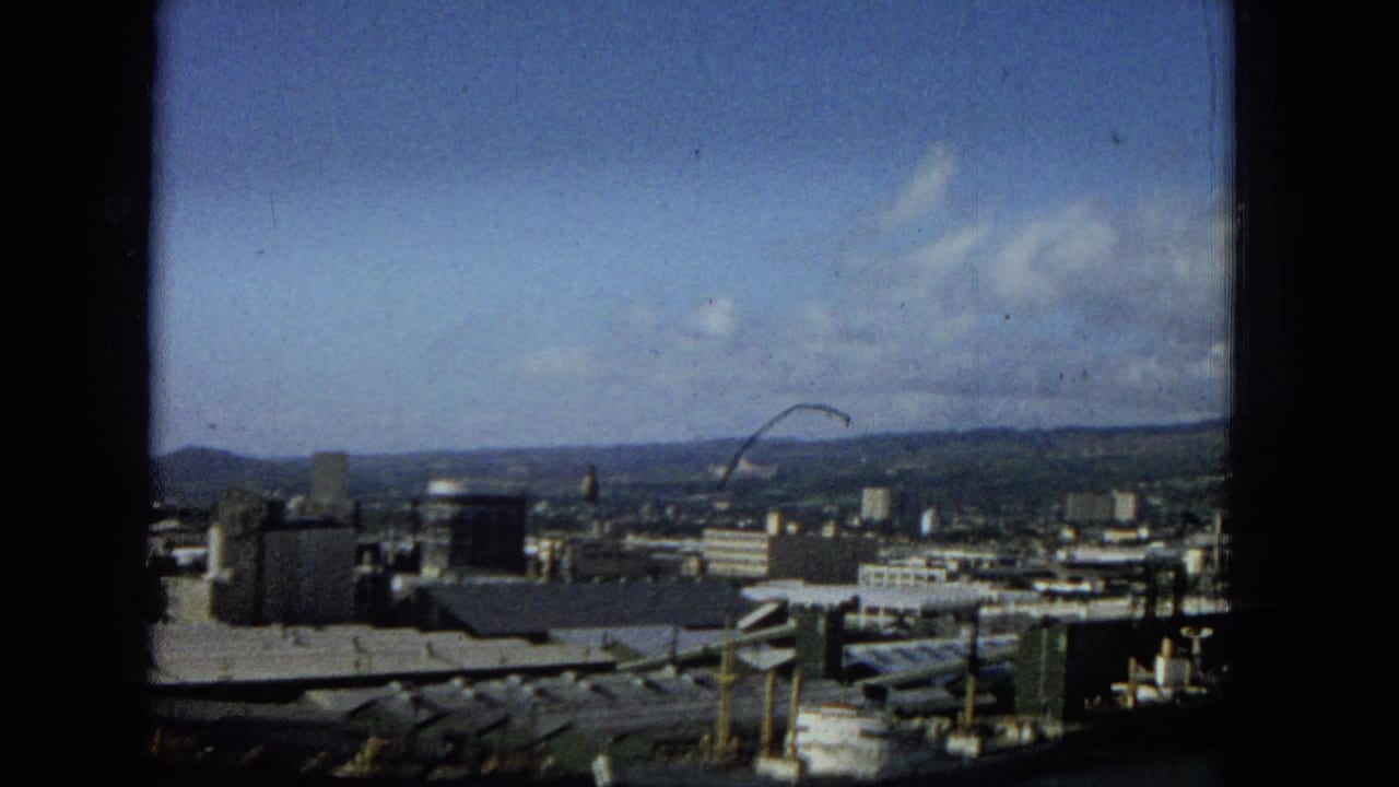 Urban waterfront and distant hills viewed through a window opening.