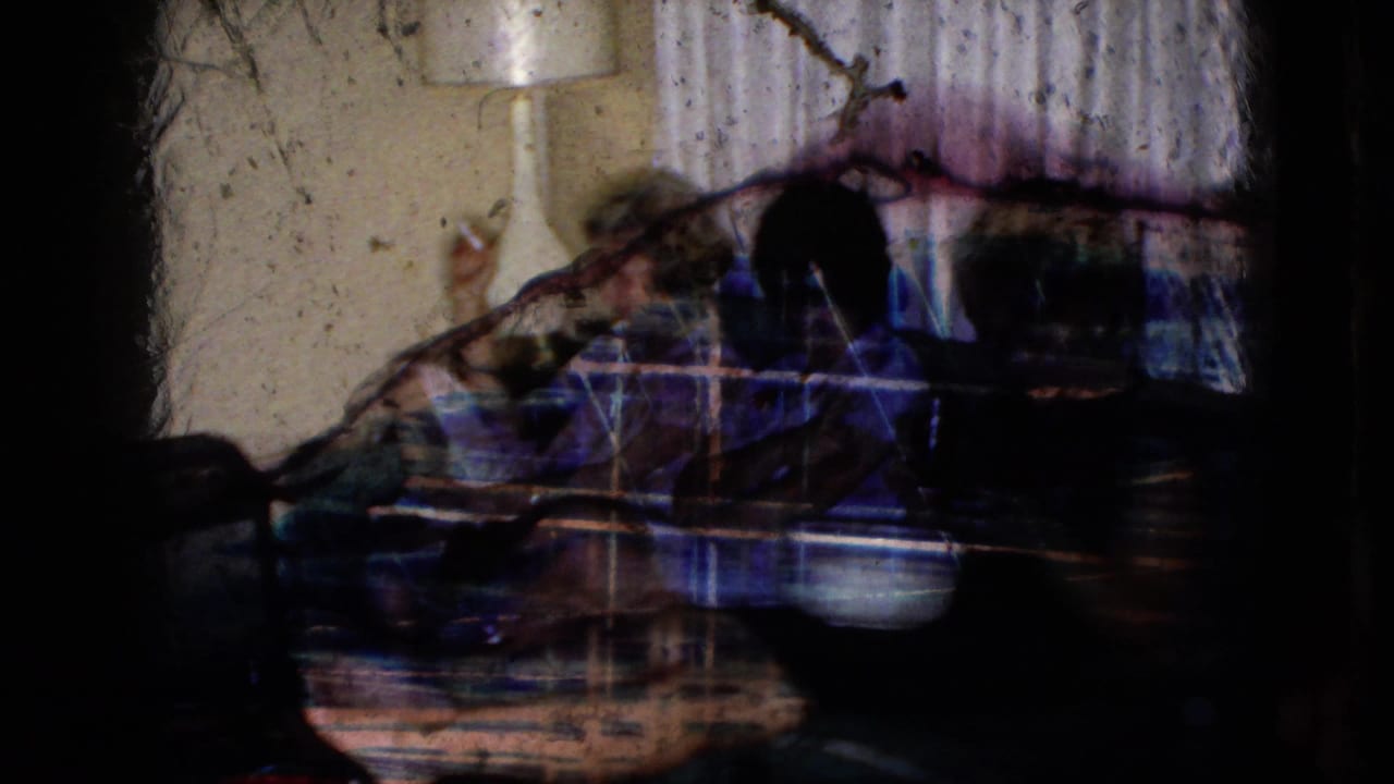 A dark, abstract overlaid frame partially shows the couch scene through film streaks and shadows.