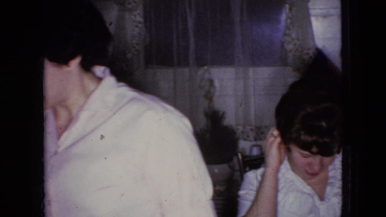 Adult in a light shirt turns away beside a table in a home interior.