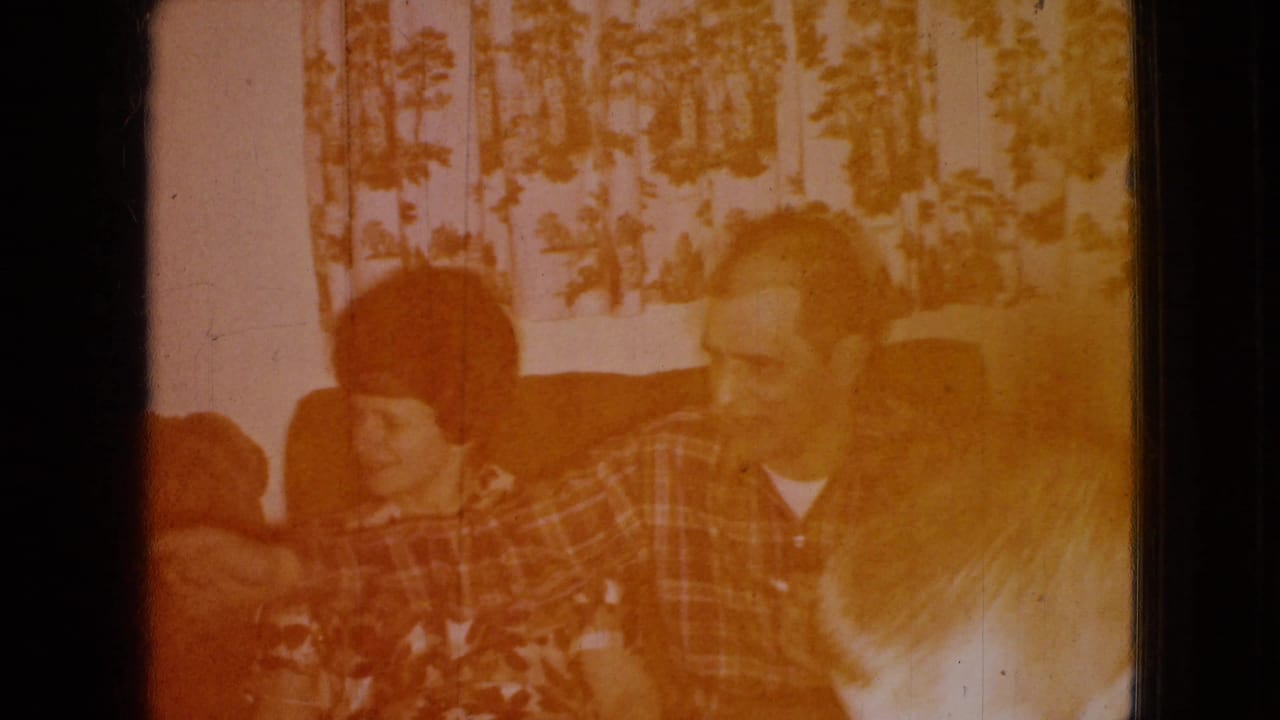 Adults seated on a couch in a warm, faded living-room frame.
